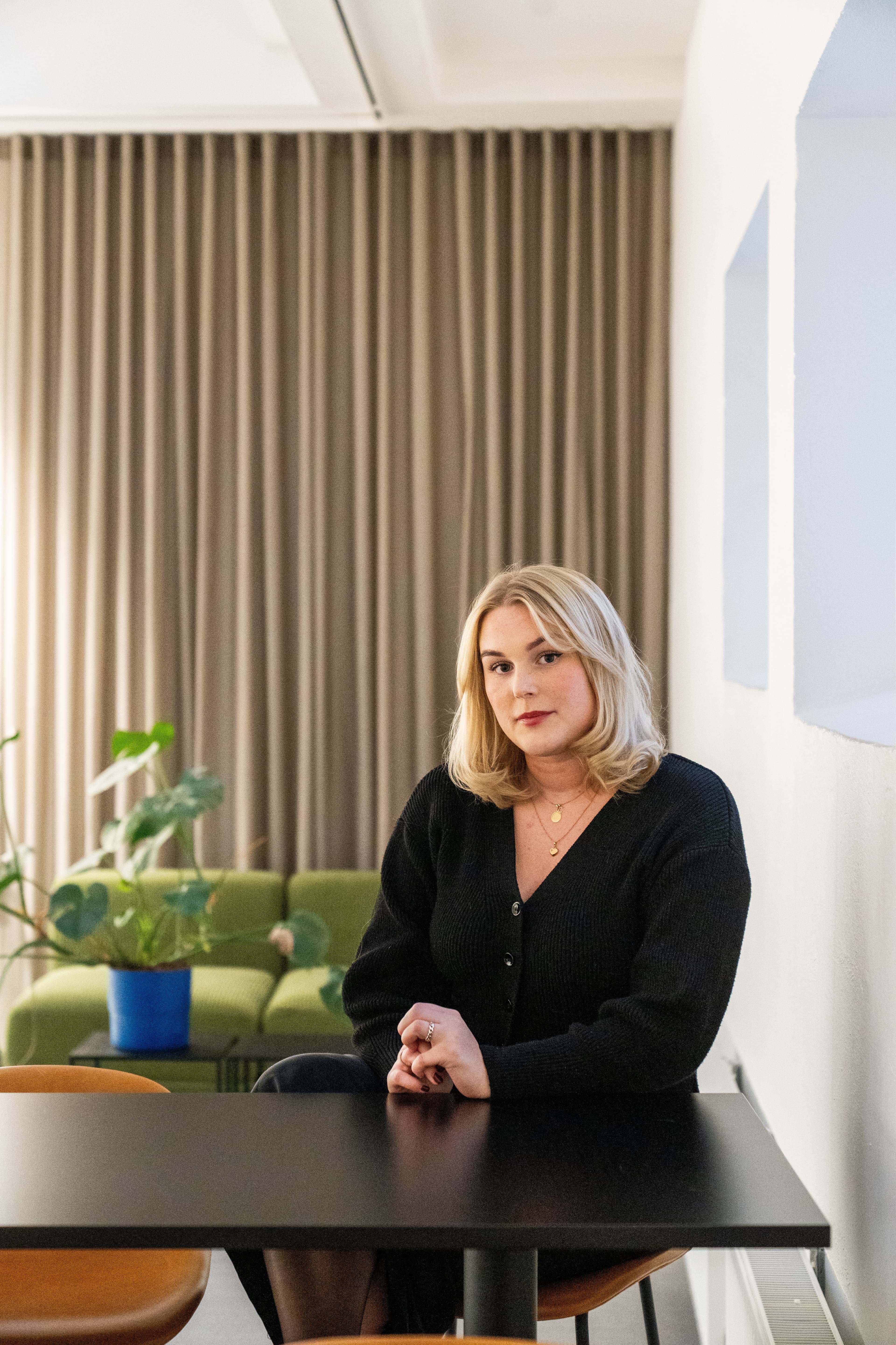 Cajsa-Stella sitter på en brun stol vid ett svart bord i kontorsmiljö.