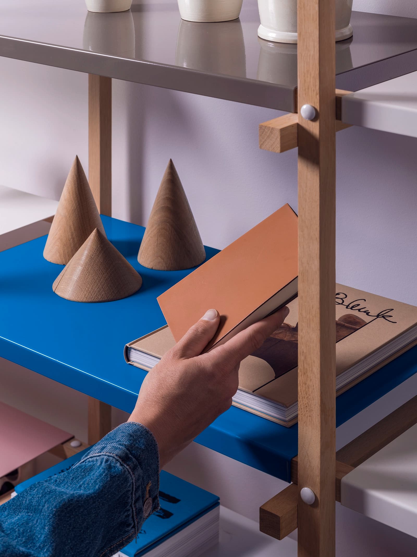 Hand som sträcker sig efter en bok från en bokhylla. 